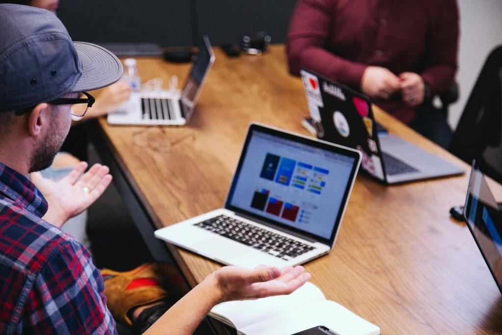 A digital marketing team collaborating on a campaign strategy with a laptop showing contest landing page designs and creative planning notes.